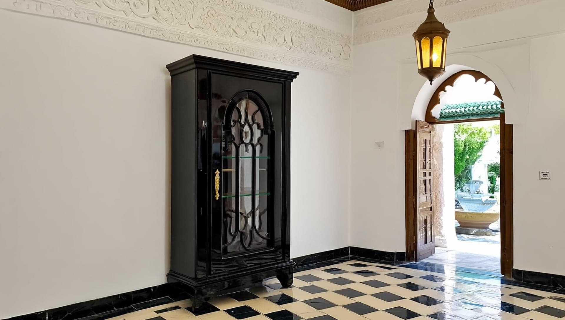 AZ Ameublement black display cabinet in a gallery with carved plaster walls and a zellige floor