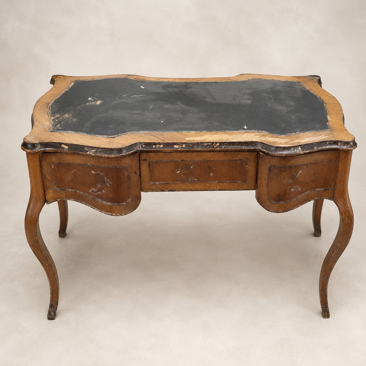 Bureau plat de style Louis XV à l'arrivée : plateau usé, écritoire noirci et chants abîmés